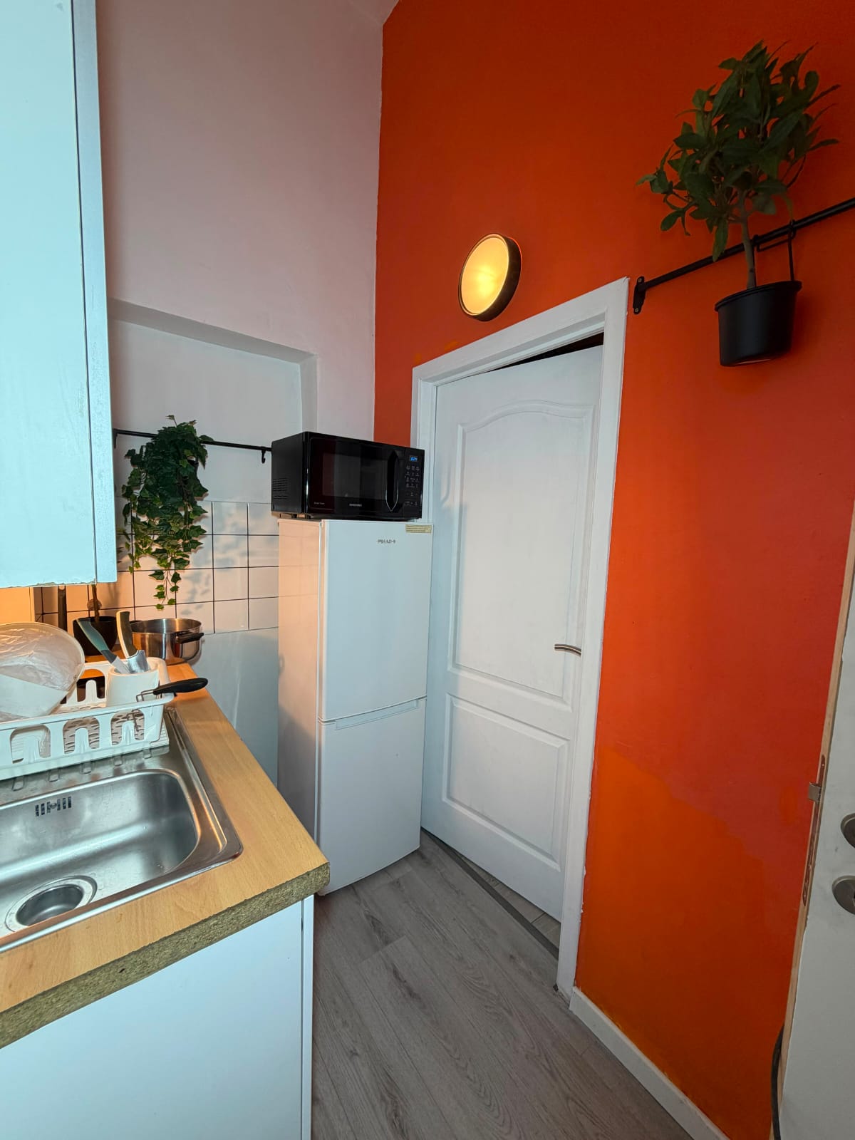 Entrée du logement avec mur orange et kitchenette