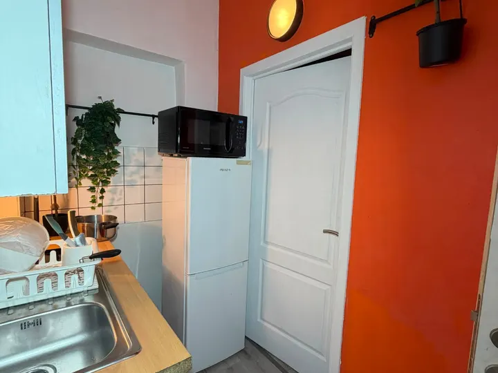Entrée du logement avec mur orange et kitchenette