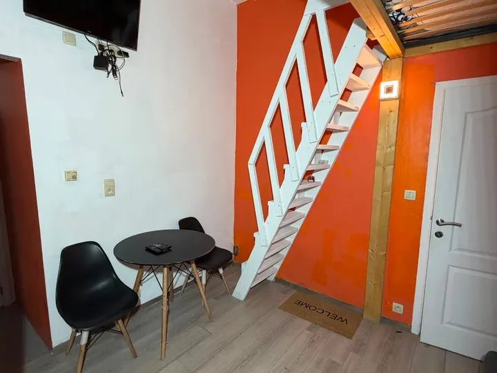 Coin repas avec table, chaises, télévision et escalier